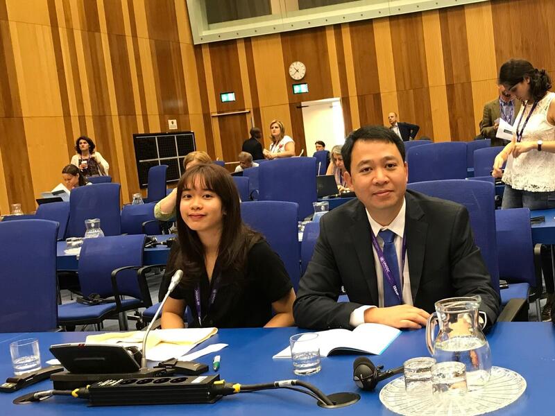A young woman and an older man sitting next to each other at a table. 