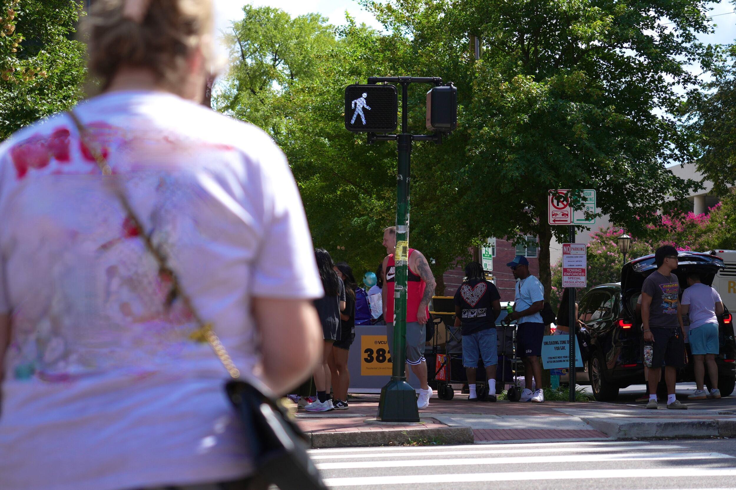 A photo of a corsswalk with people standing on the sidewalk. 
