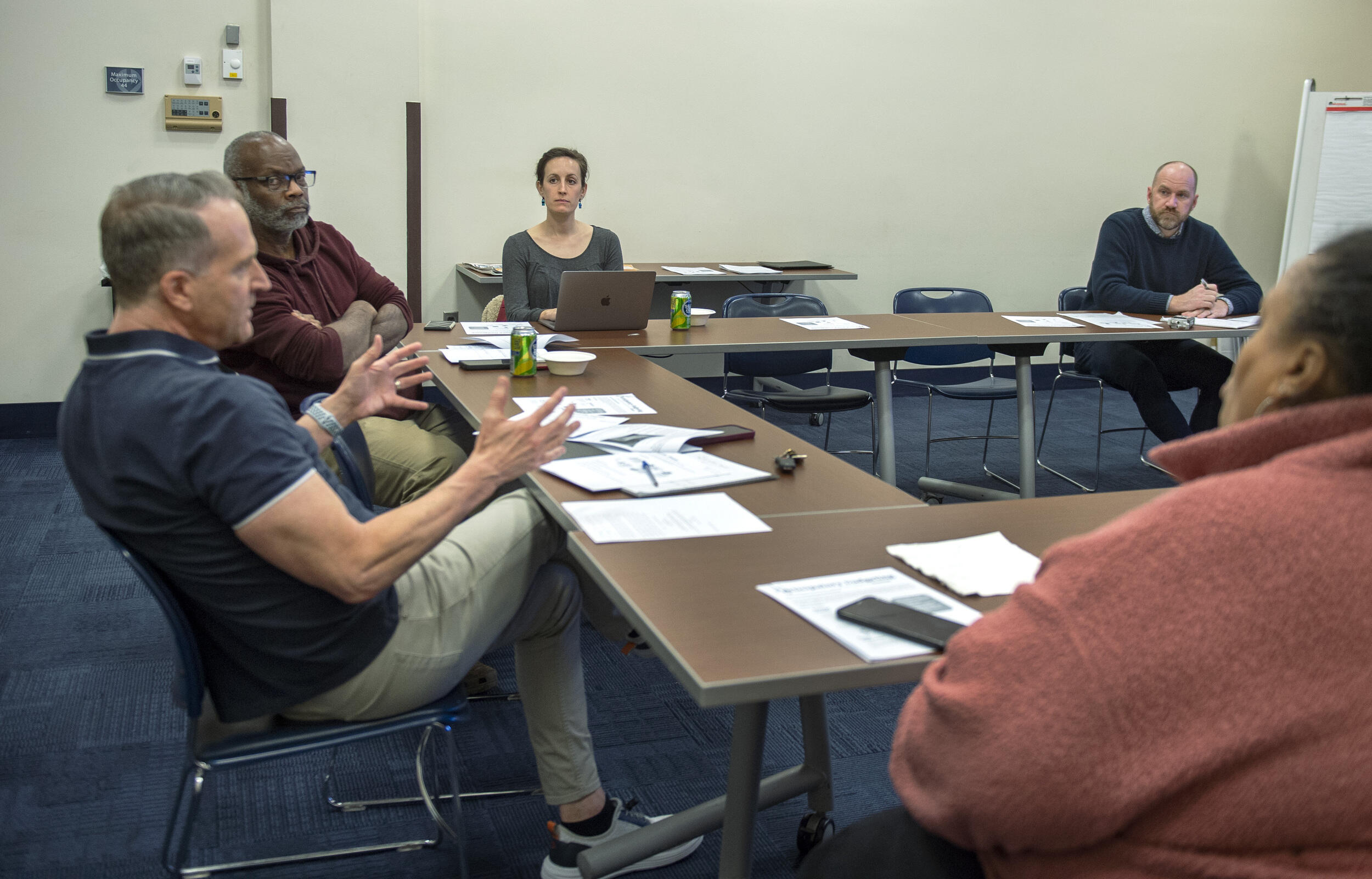 Five people sitting at tables set up into a u shape. 