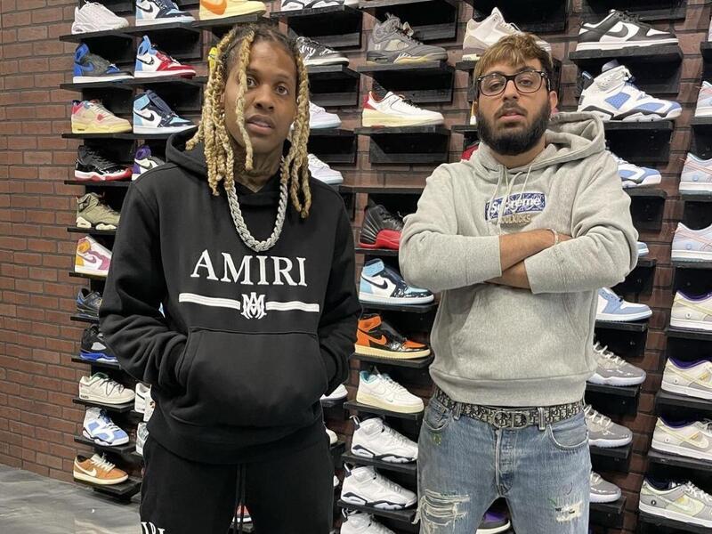 Two men standing next to each other in front of a display of sneakers. 