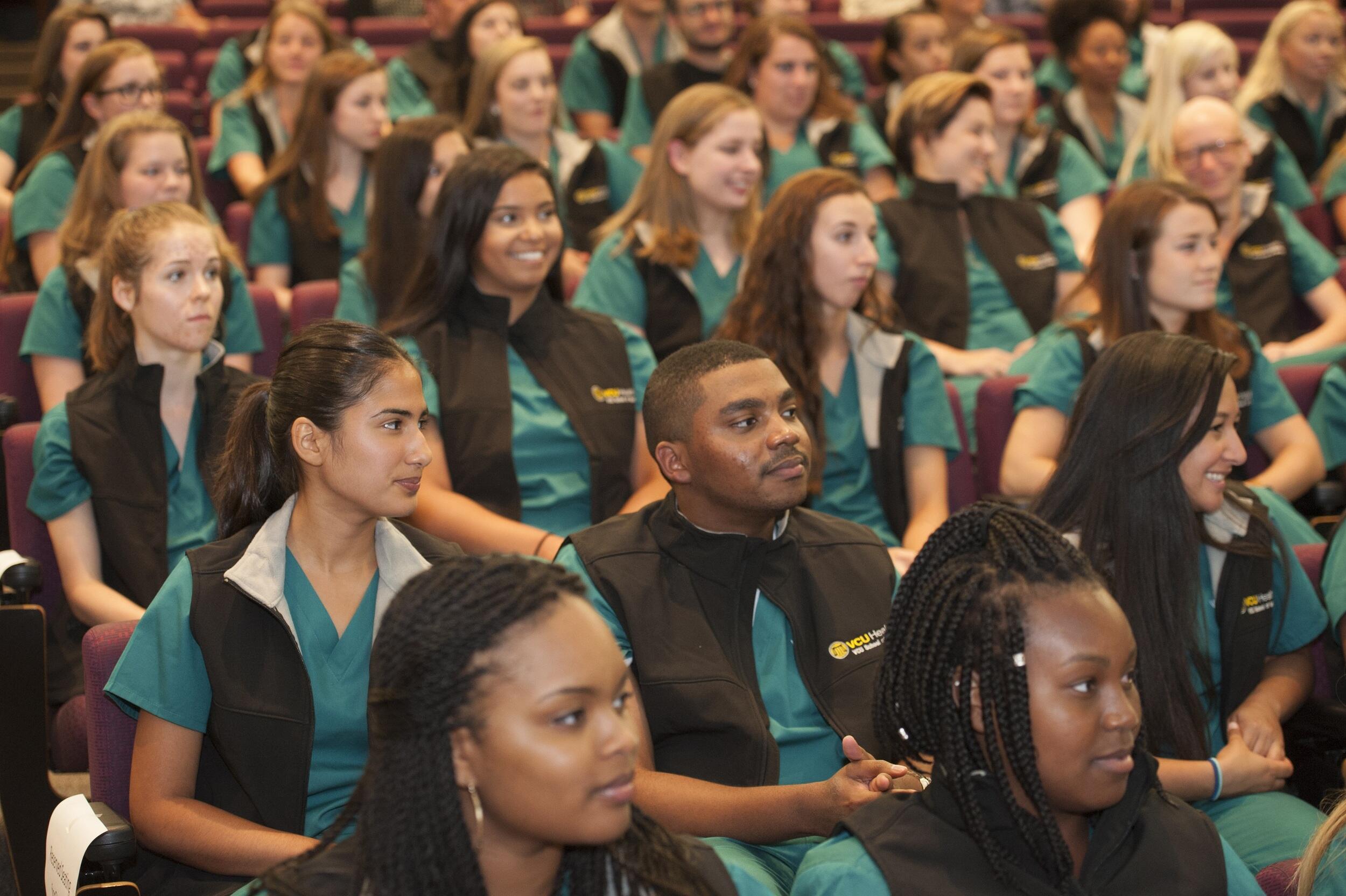 A crowd of people wearing green scrubs and black vests