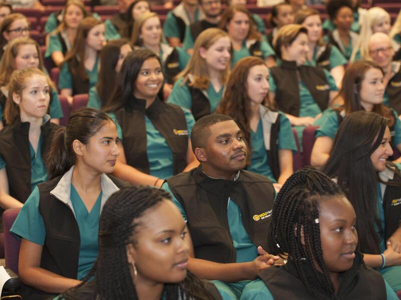 A crowd of people wearing green scrubs and black vests