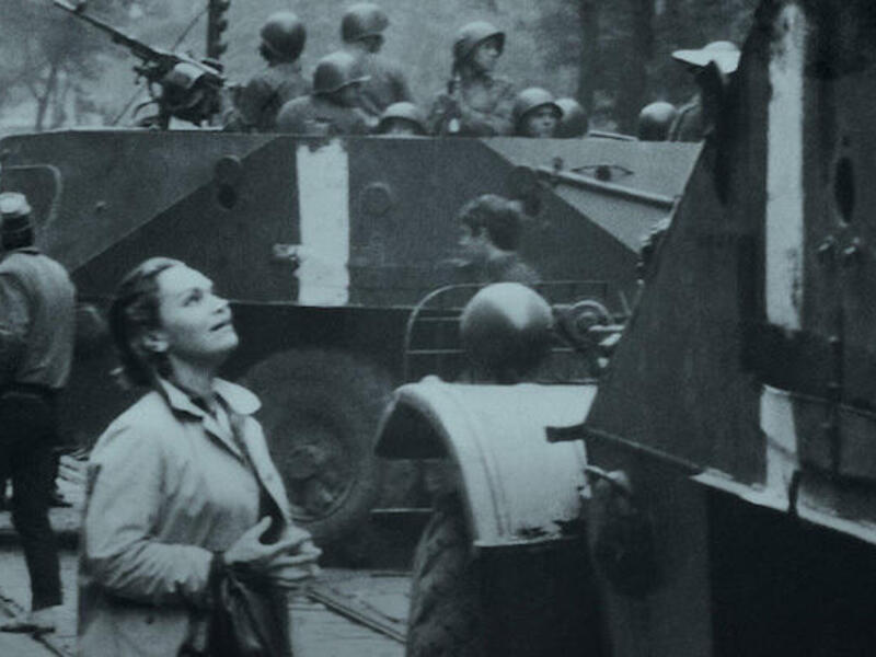 A woman looks up at an armored vehicle.