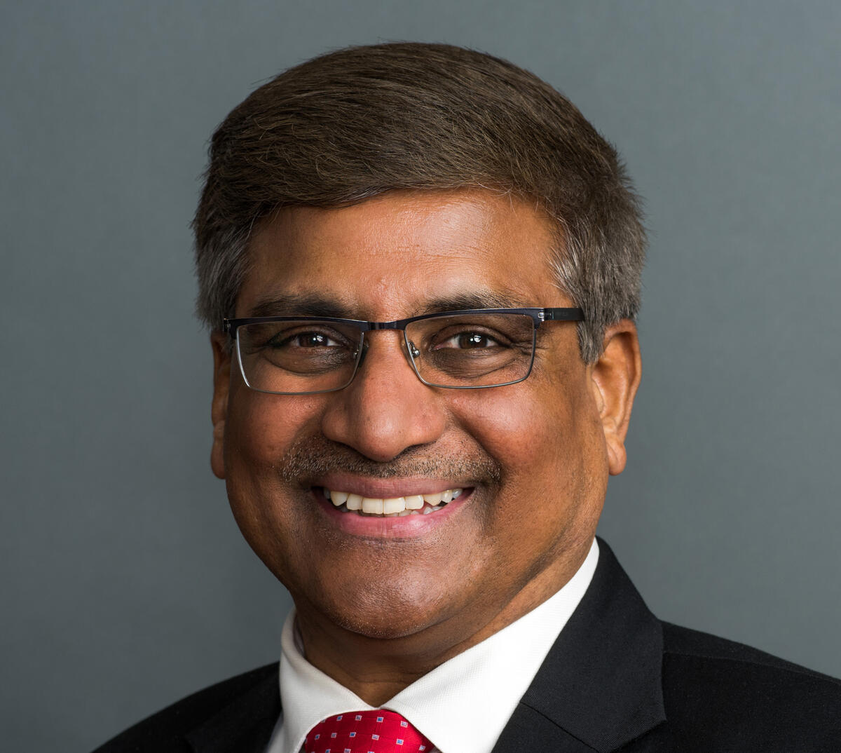 A photo of a man wearing a suit and tie from the chest up. 