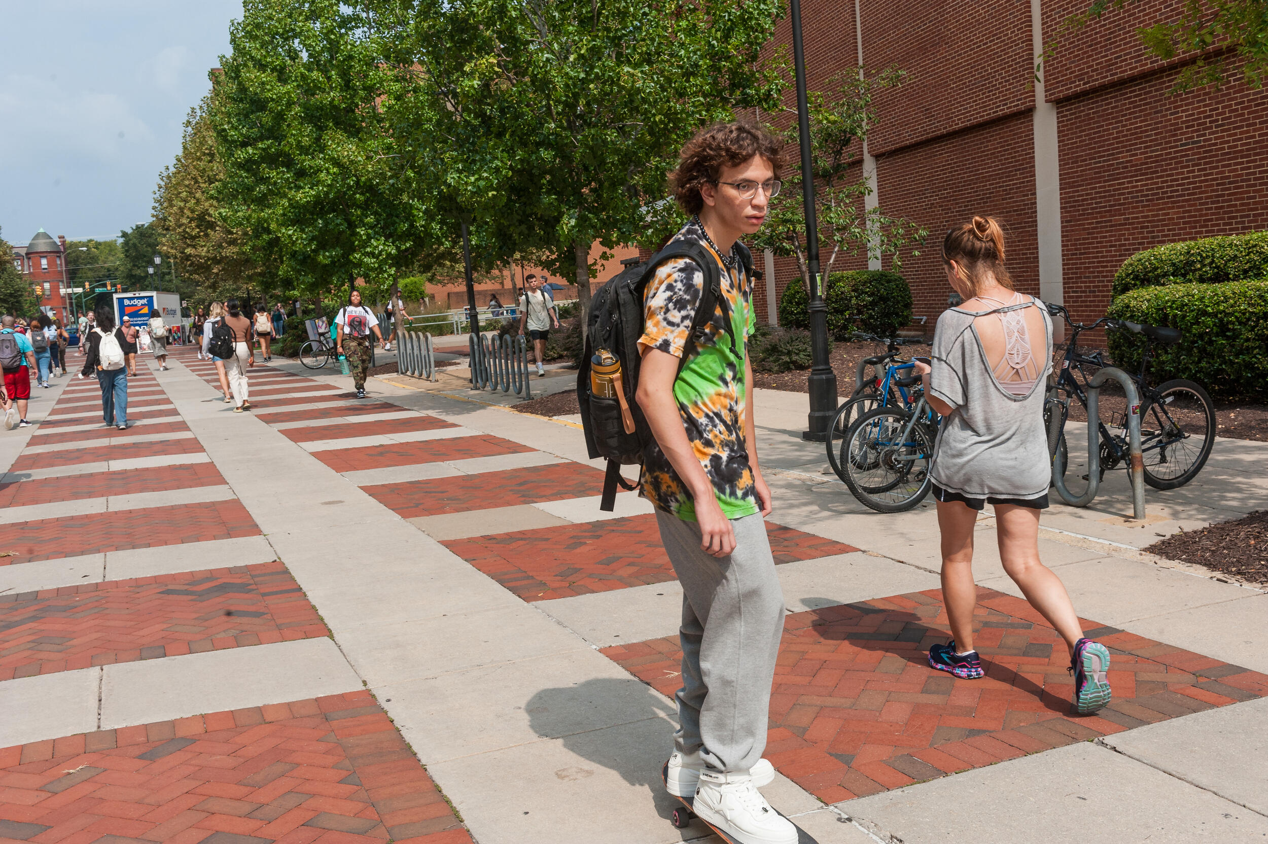 A photo of a man riding a skateboard down the sidewalk. 