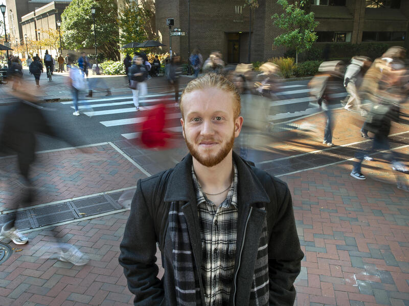 A photo of a man standing on a sidewalk. 