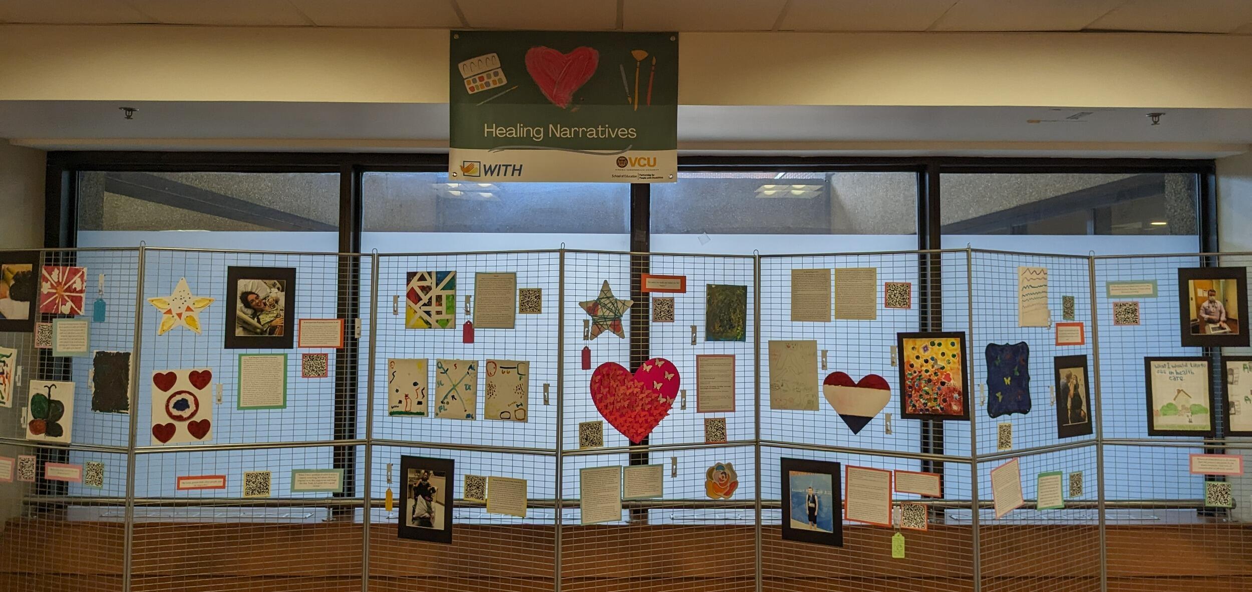 A photo of a metal grated divider with artwork hung up on it. 