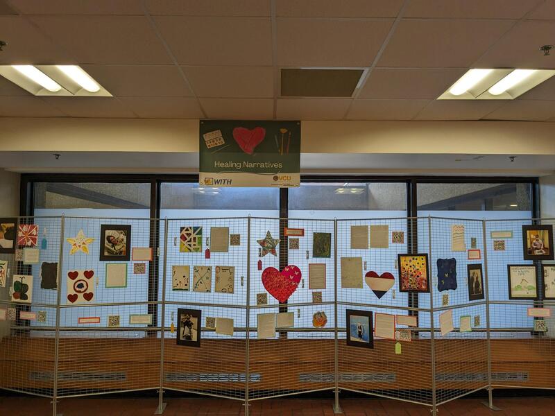 A photo of a metal grated divider with artwork hung up on it. 