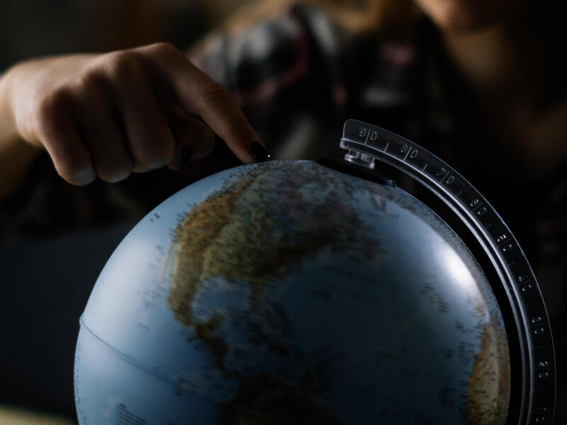 A person points to a globe map.