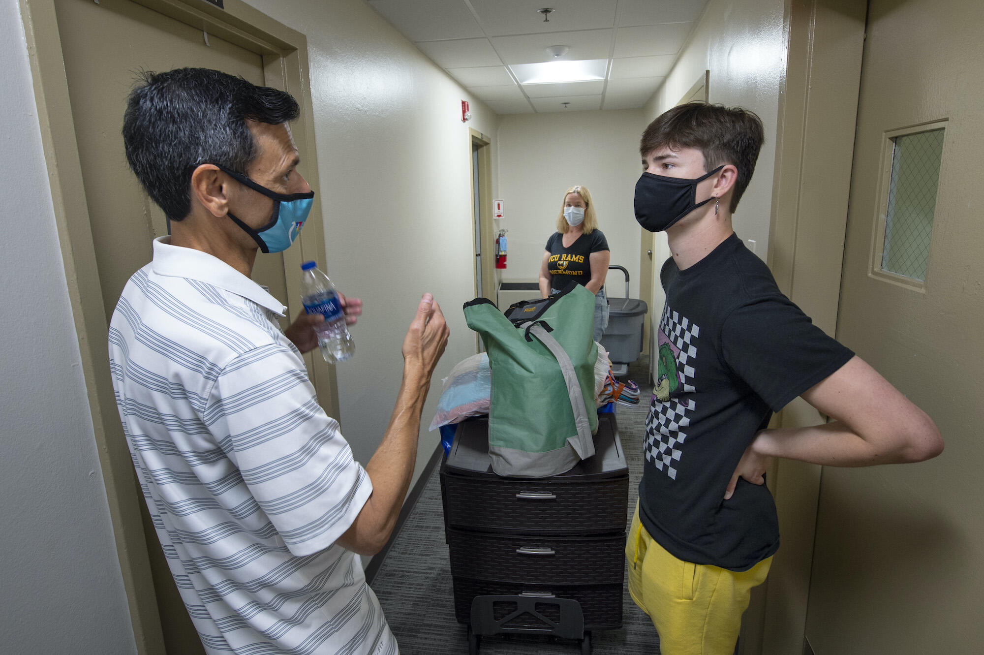 VCU President Michael Rao speaks with VCU student Aiden Rafa who was getting help moving in from mother, Karen Rafa (back center).