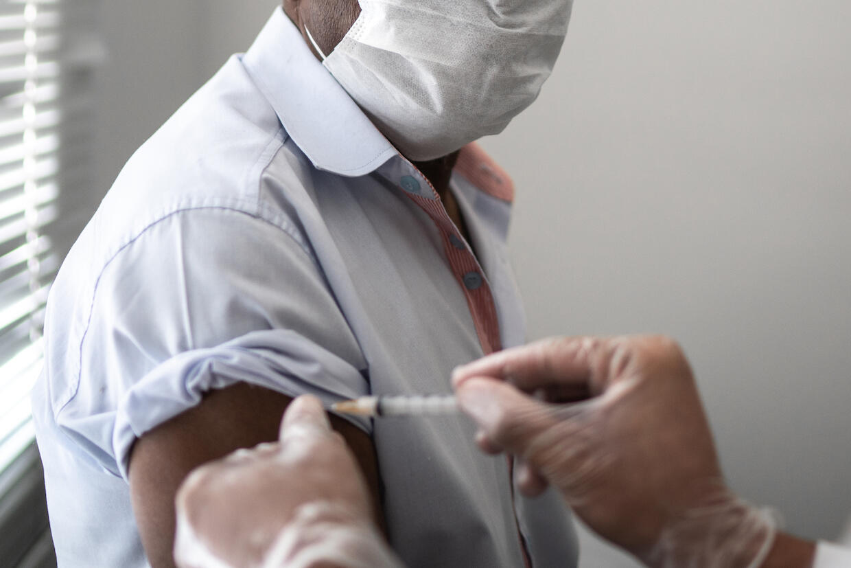 A person wearing a mask receives a vaccination shot.