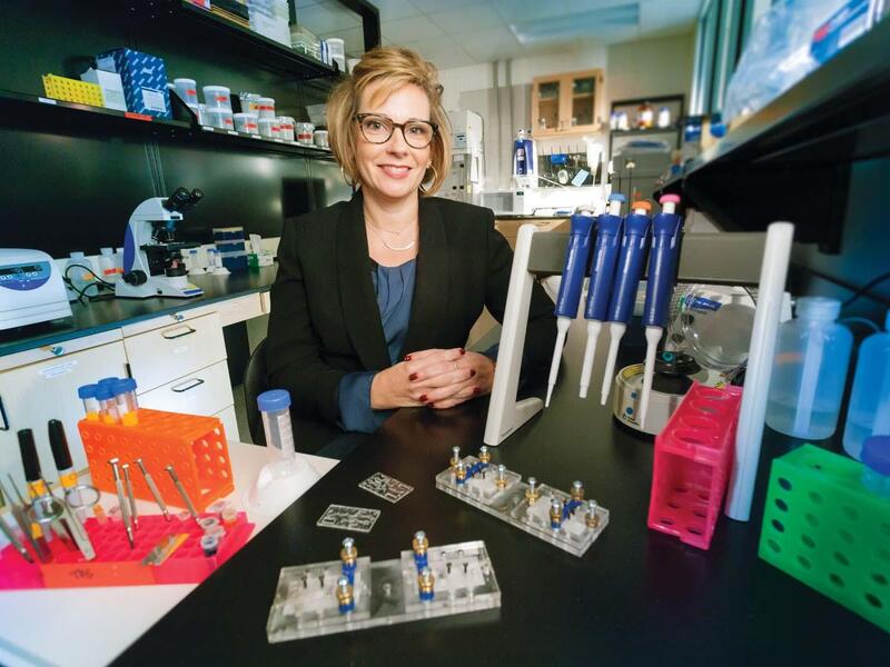 Tracey Dawson Cruz, Ph.D., sitting in a medical laboratory room.