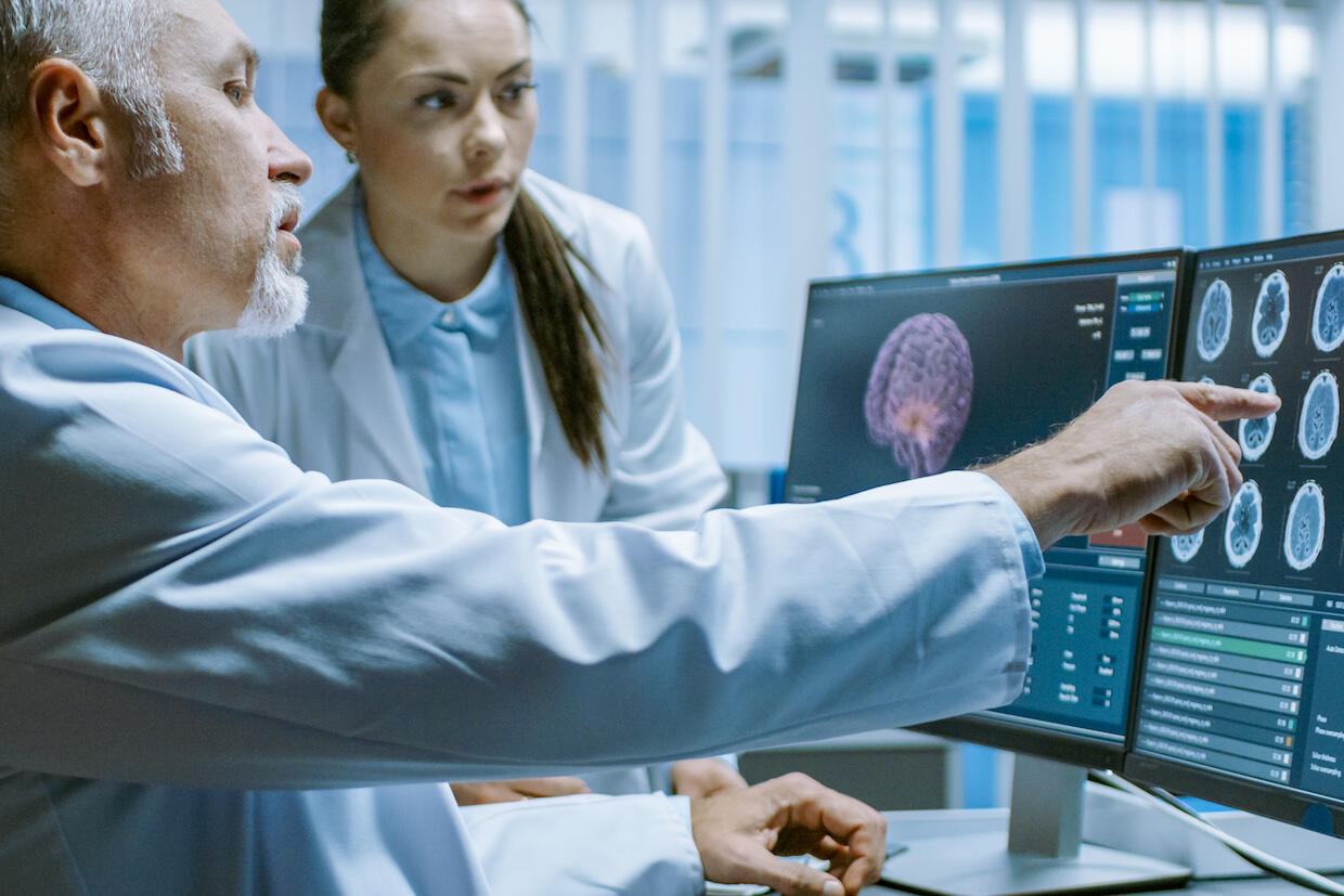 Two people look at a computer screen displaying medical scans.