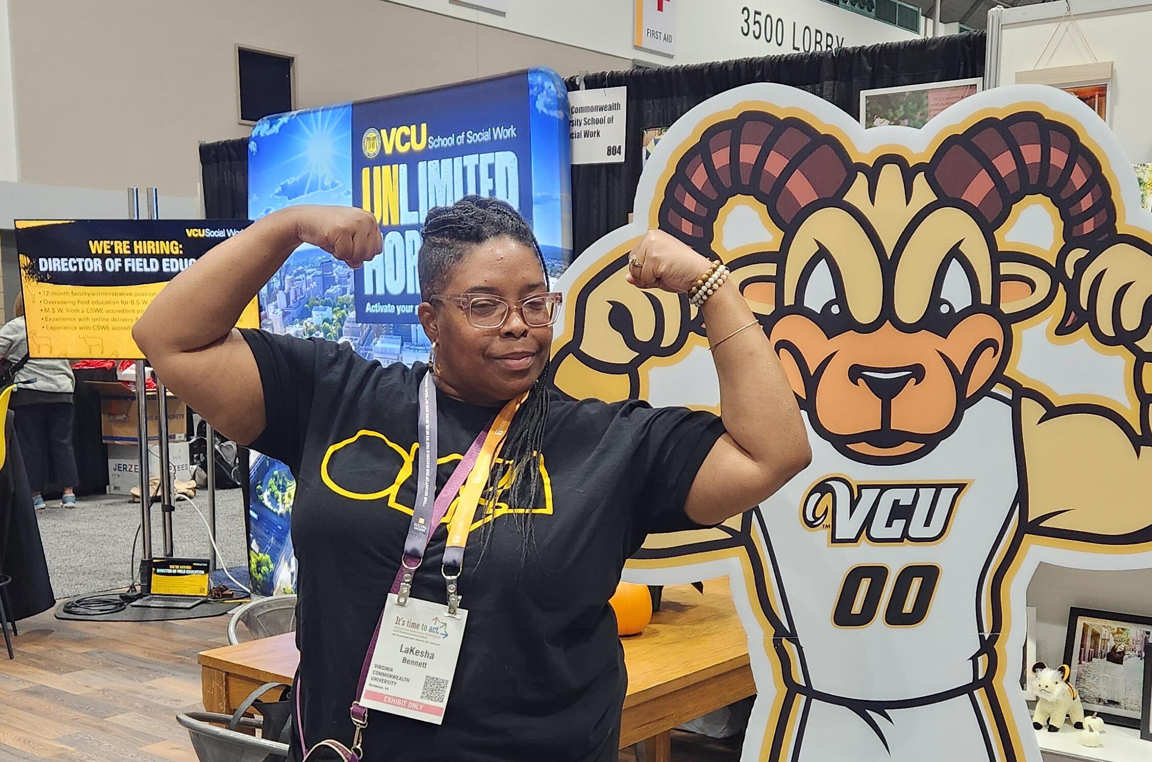 A photo of a woman posing next to a cardboard cut out of Rodney the Ram. 