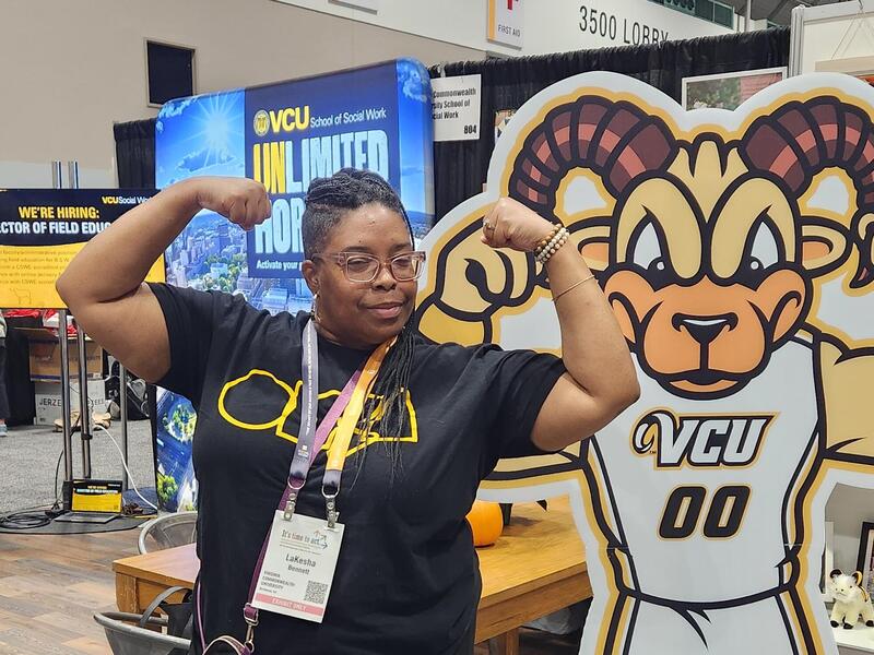 A photo of a woman posing next to a cardboard cut out of Rodney the Ram. 