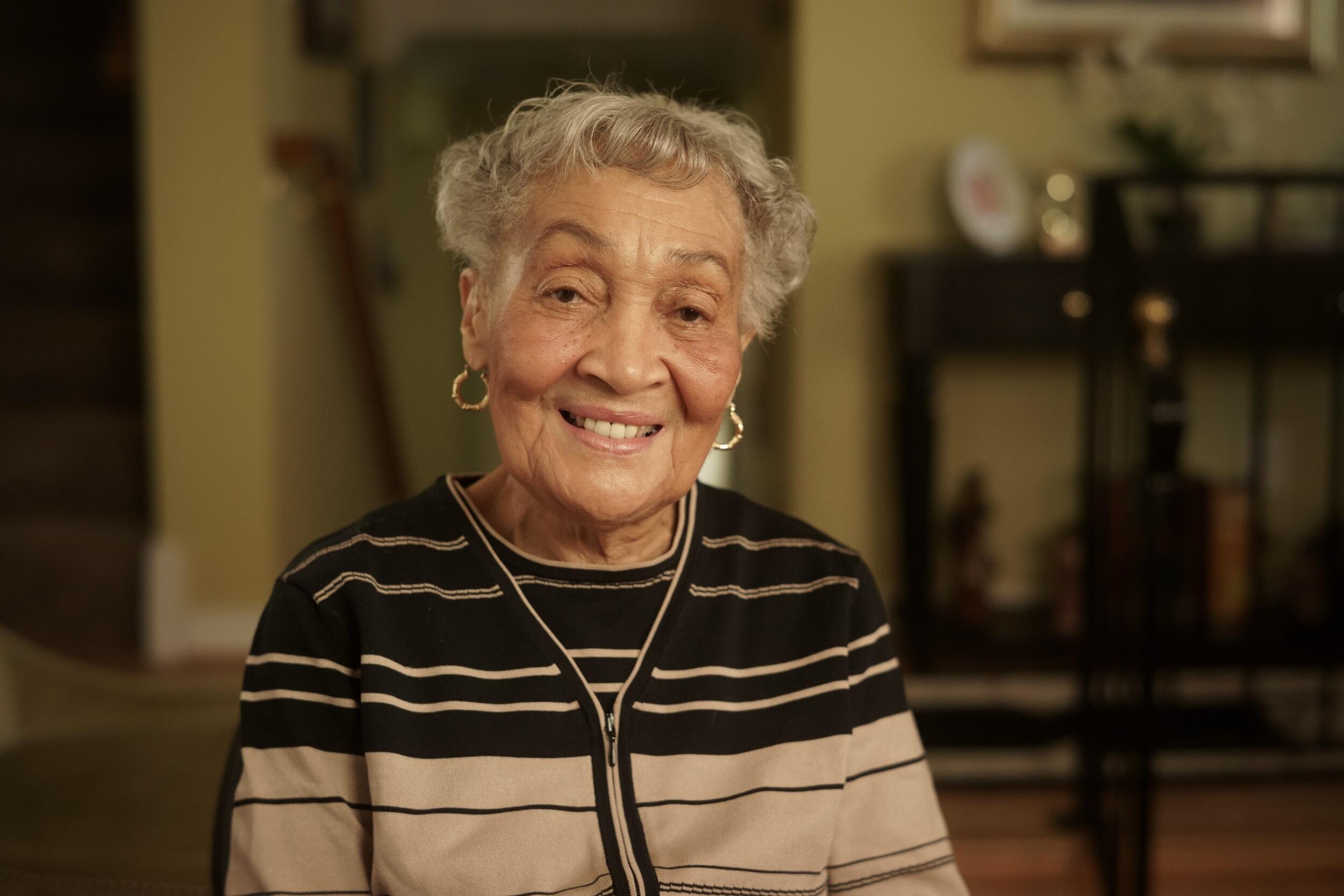 Florence Smith smiling wearing a brown and beige striped cardigan