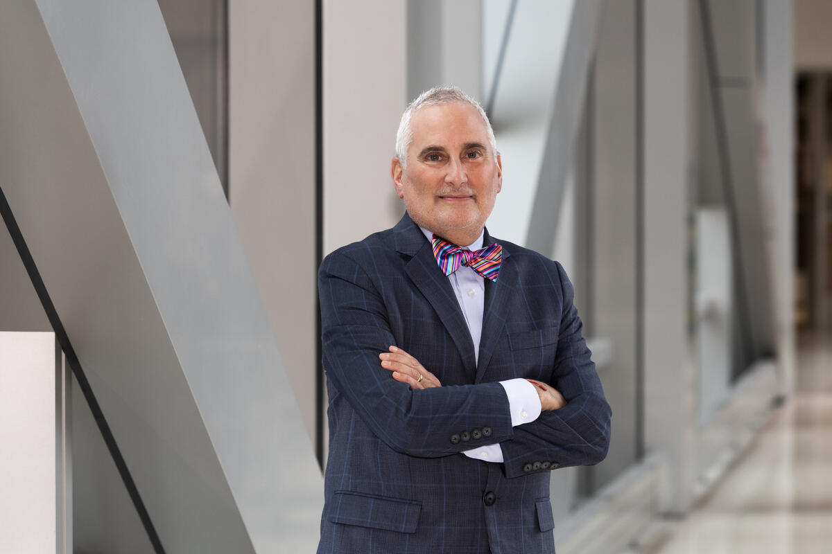 Neri Cohen standing with his arms crossed in a hallway