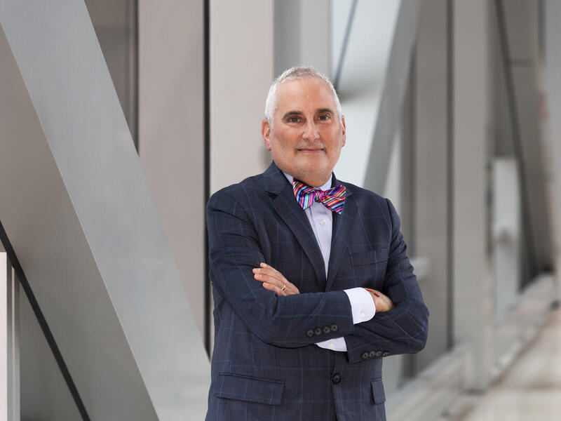 Neri Cohen standing with his arms crossed in a hallway