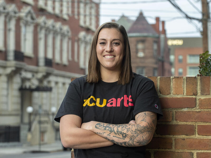 Leah Agler standing in front of a brick wall.