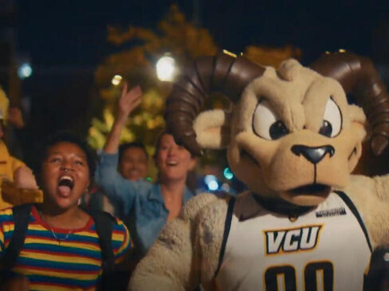 A photo of people cheering around a Rodney the Ram mascot. 