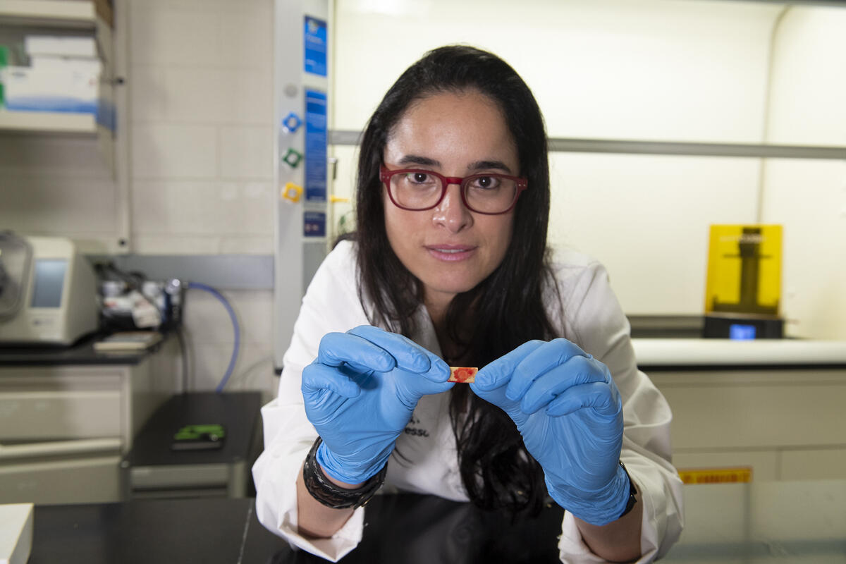 A photo of a woman wearing blue gloves holding a small red and yellow object in her hands.