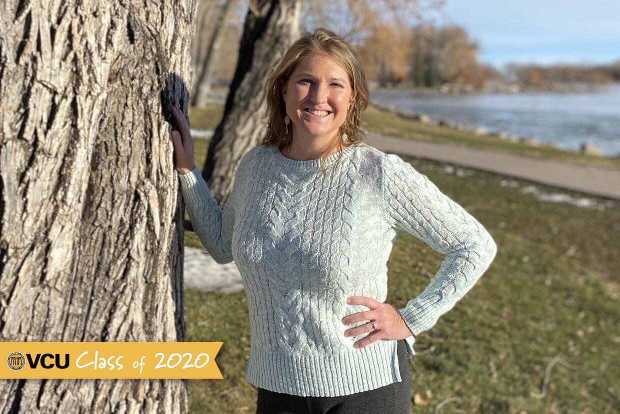 Woman standing and leaning next to a tree