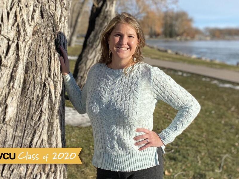 Woman standing and leaning next to a tree
