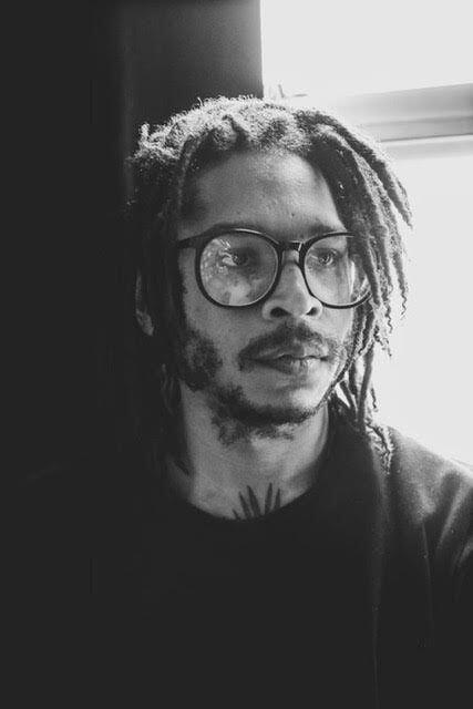 Close-in portrait of Jeremy Toussaint-Baptiste, situated in front of a window.