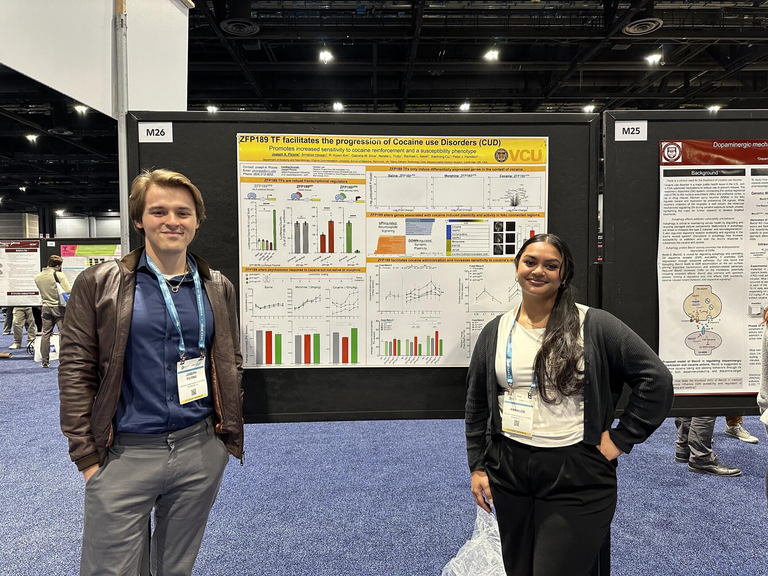 A photo of two people standing on either side of a poster showing research findings. 