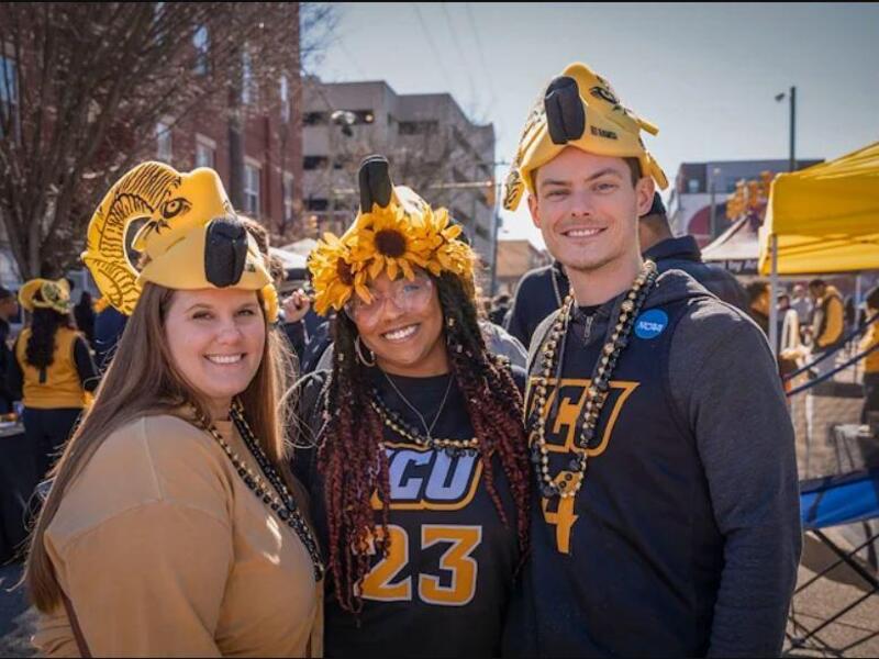 Three people standing outside at a Block Party wearing VCU swag