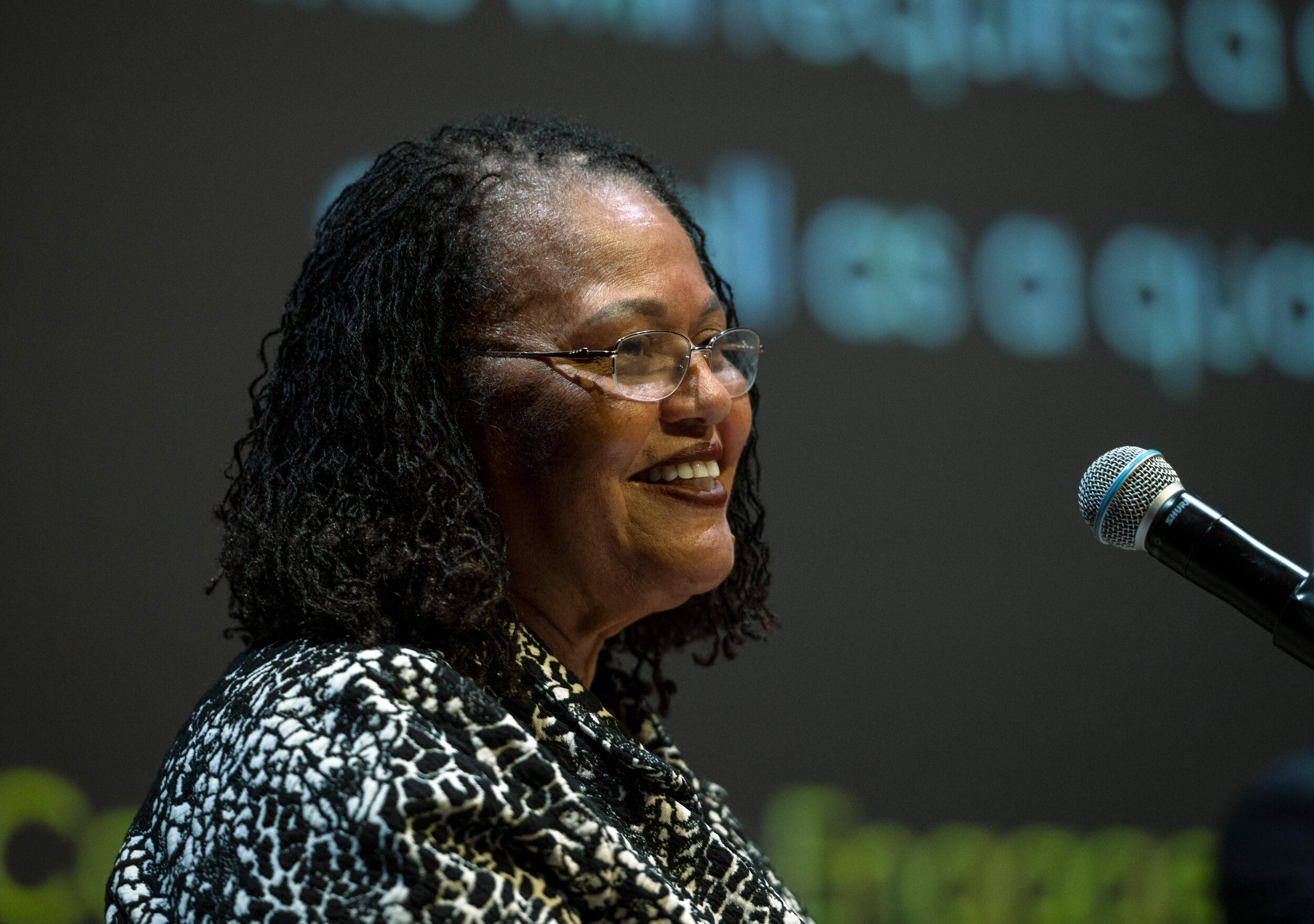 A woman smiles behind a microphone.