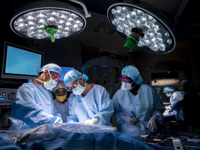 Four people in scrubs perform surgery.