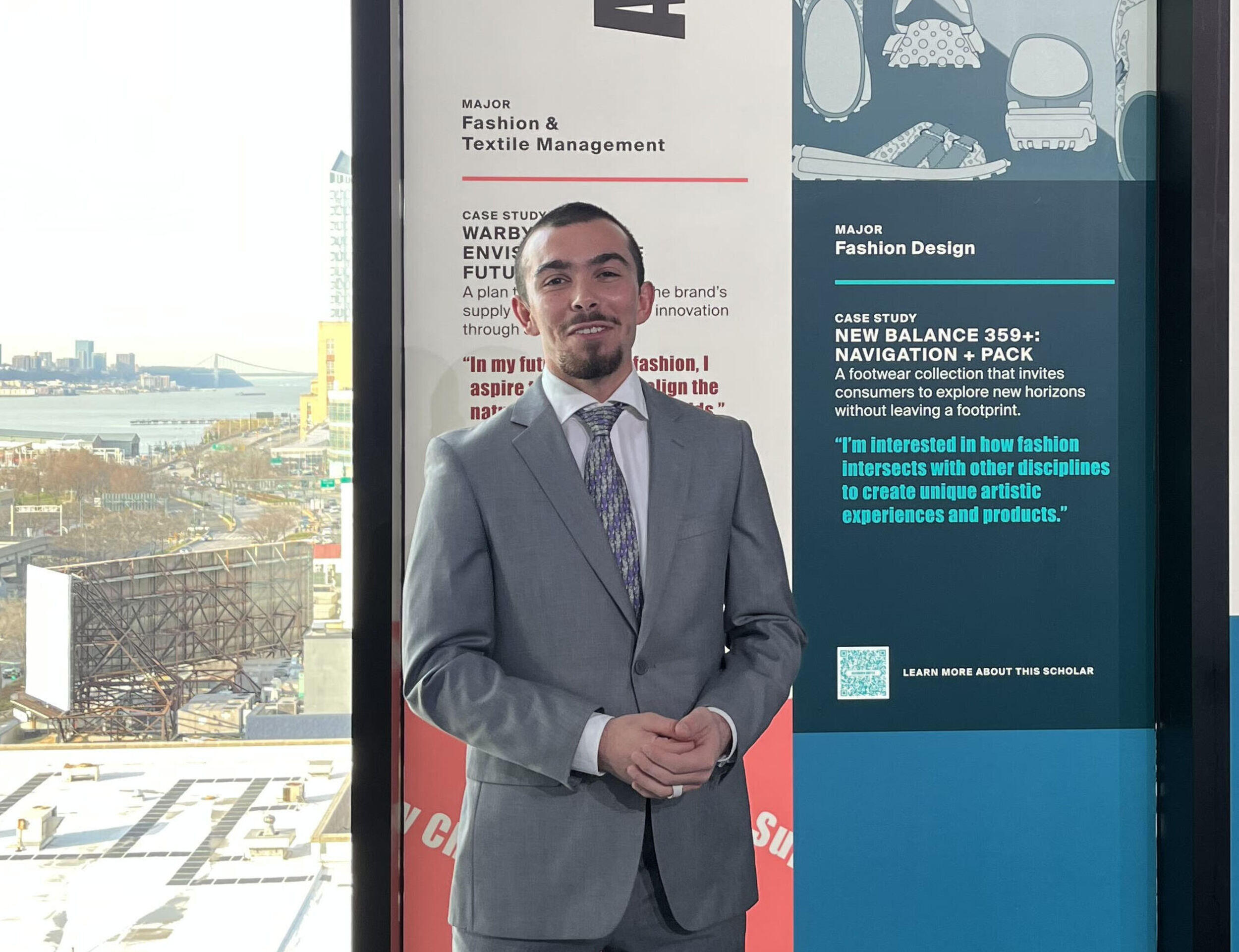 Alexander Britto standing in front of floor to ceiling windows, some of which are covered in graphics 