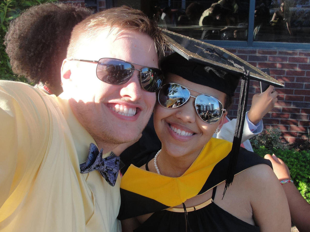 A selfie of a man in sunglasses and a woman wearing a graduation cap and gown. 