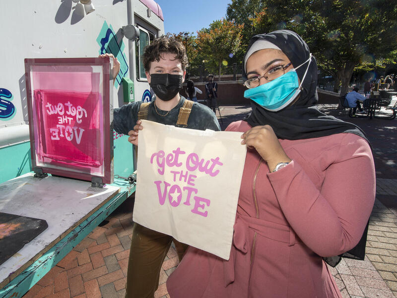 Students hold up screen-printed tote bags at a VCU Votes event on Oct. 27. 