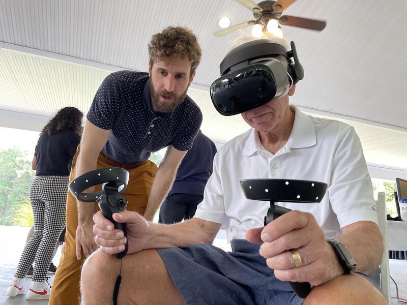Alexander Stamenkovic, a post-doctoral fellow in the Motor Control Lab, assists Ray Birk as Birk uses a VR headset and hand controls.