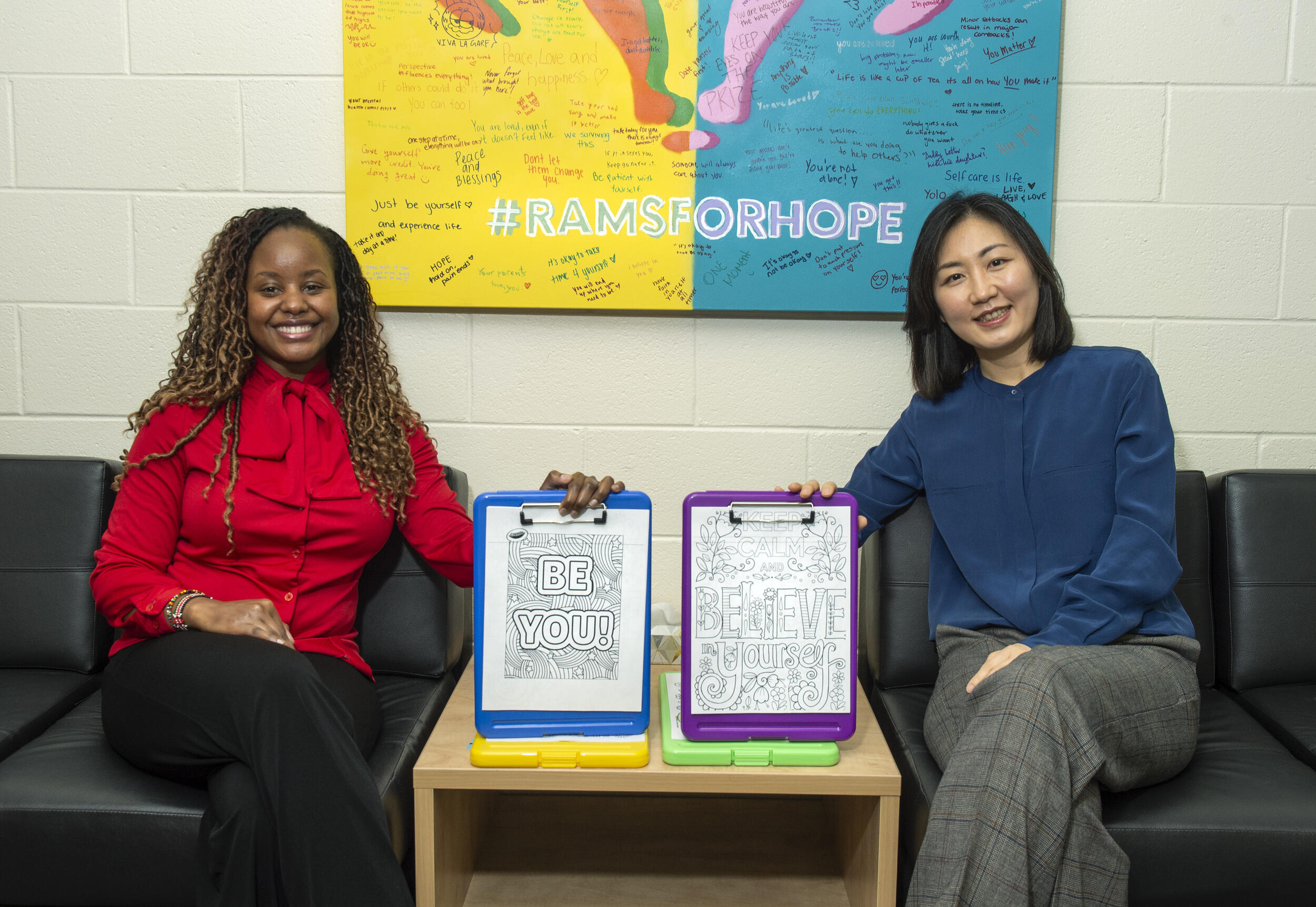 Two women sitting in chairs holding clips boards 
