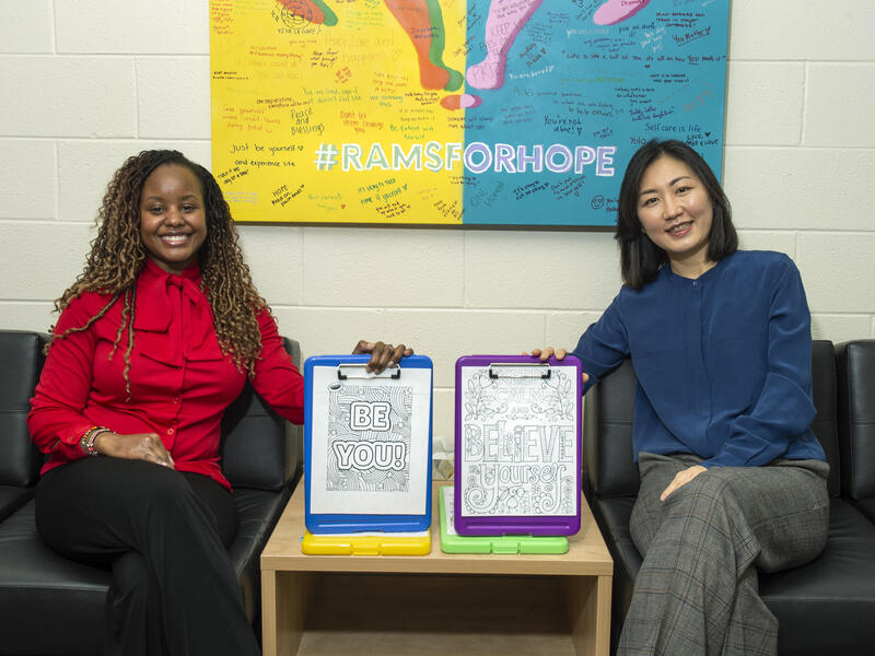 Two women sitting in chairs holding clips boards 