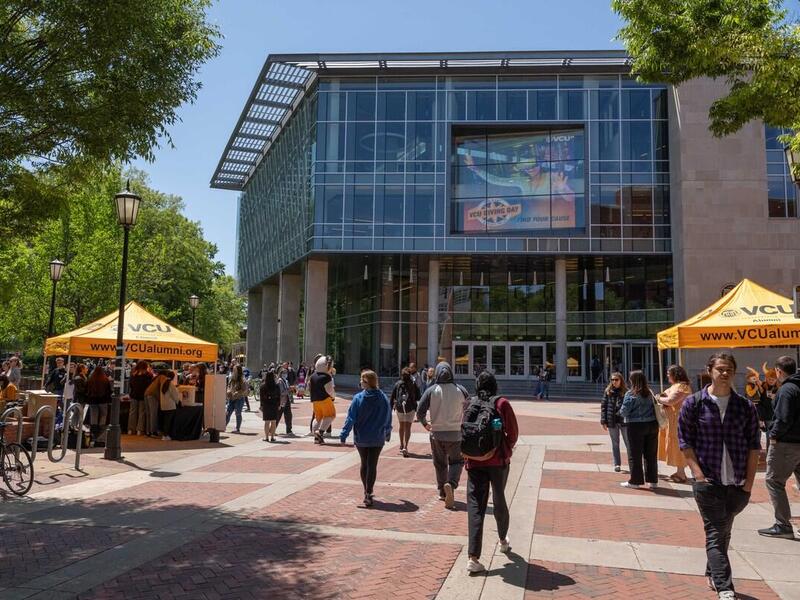 A view of cabell library from the compass with people walking around and two yellow tents set up