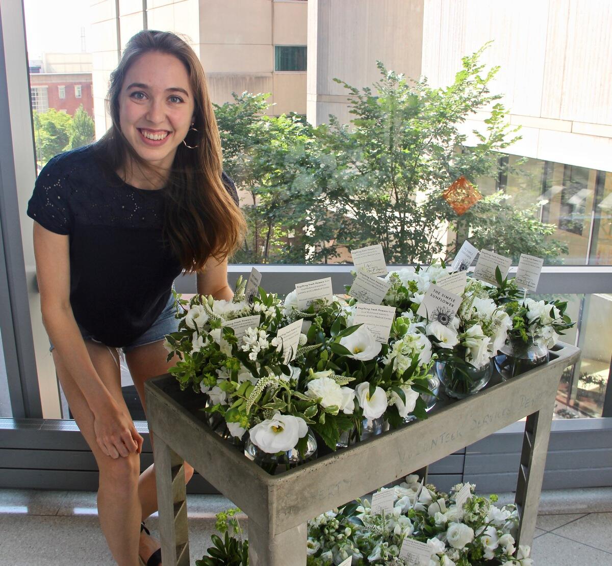 Eleanor Love poses next to a cart full of flowers.