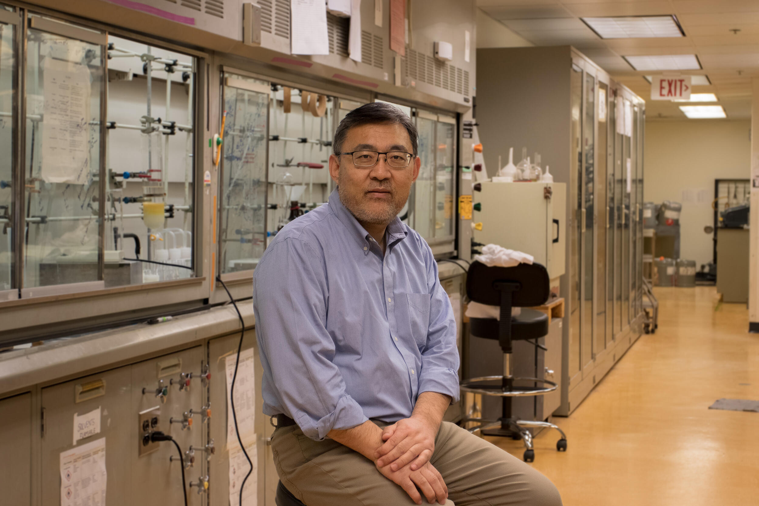 A photo of a man sitting on a stool in a lab