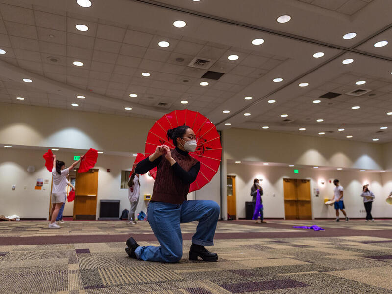 Students in the Vietnamese Student Association practice a dance routine using traditional props such as umbrellas, fans and hats. 
