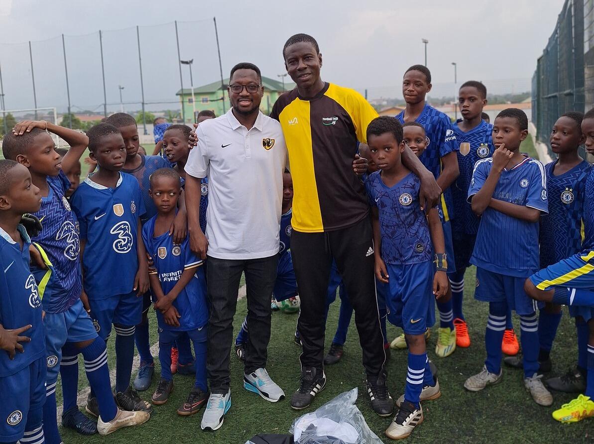 A group photo of two men in the middle of a group of boys wearing sports uniforms. 