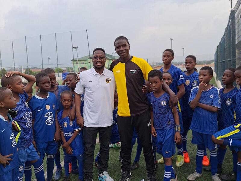A group photo of two men in the middle of a group of boys wearing sports uniforms. 