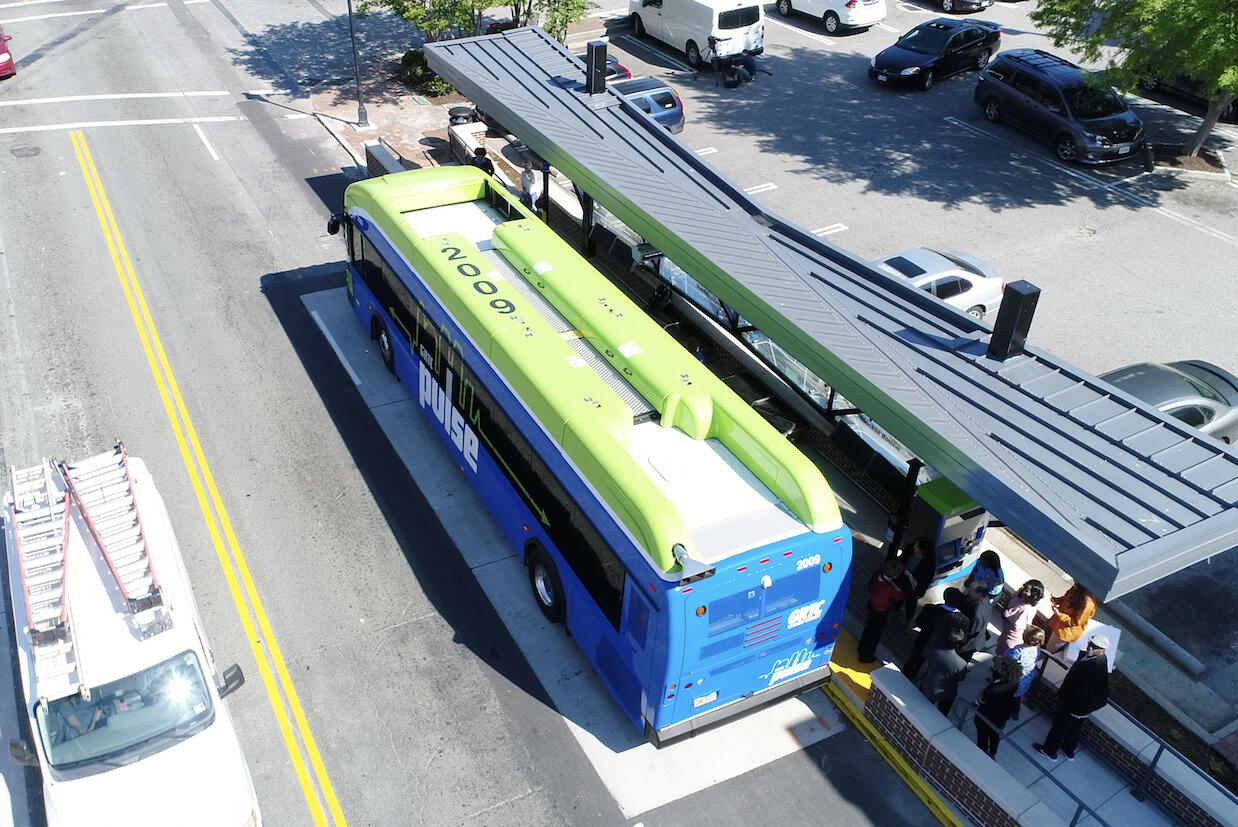 Overhead shot of a blue and green bus at a station.