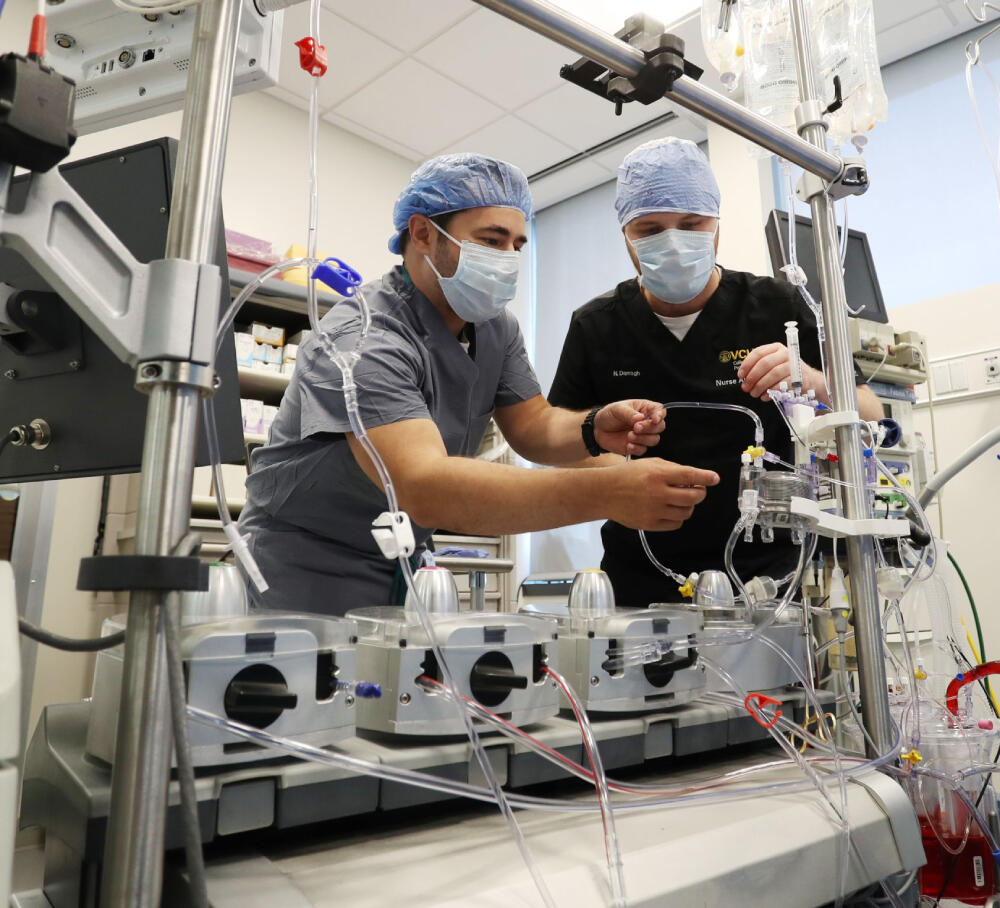 A photo of two men in medical scrubs working on equipment. 
