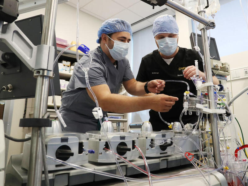 A photo of two men in medical scrubs working on equipment. 