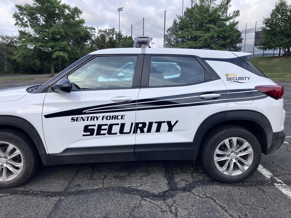 A photo of a white SUV that has black text on the side which reads \"SENTRY FORCE SECURITY.\" On the back of the vehicle is smaller text that reads \"VCU SECURITY\" in yellow and black text. 