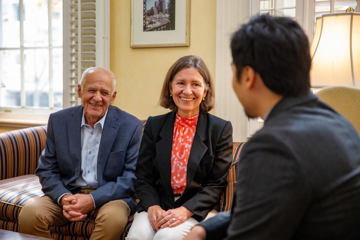 A man and a woman sitting down smiling at a man seated across from them. 