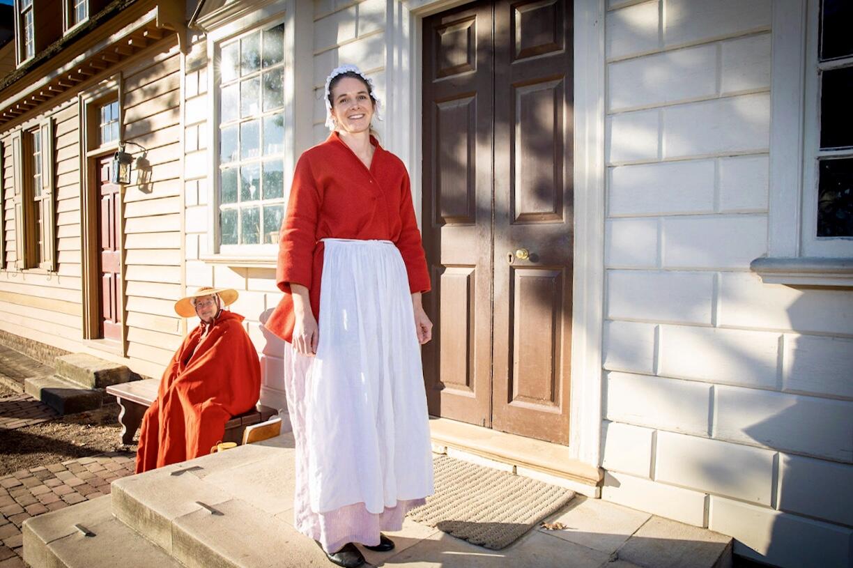 A person dressed in colonial-era clothing in front of a building.